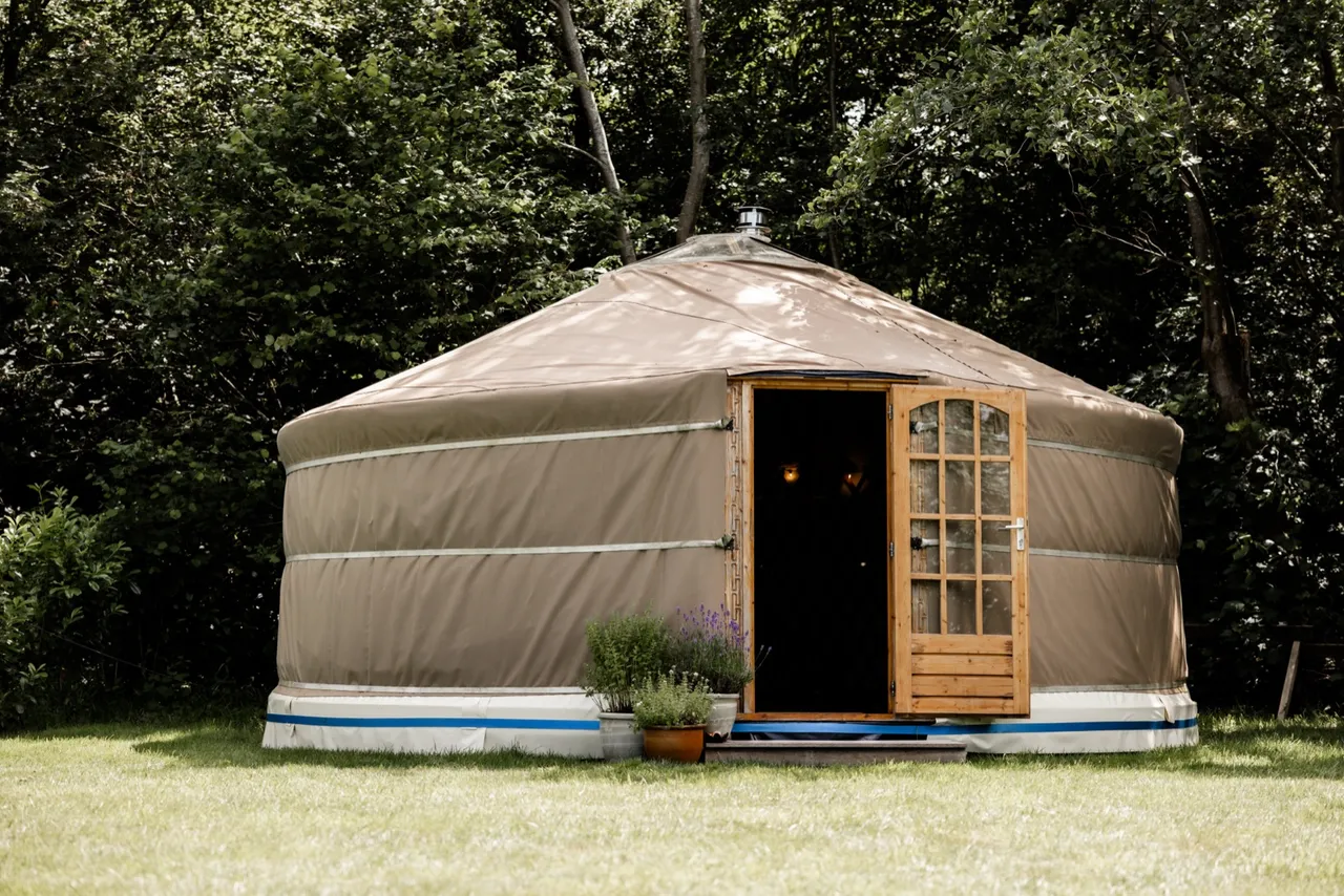 De yurt van buiten, in een rustige tuin omringd door bomen