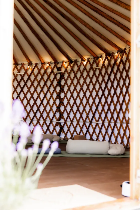 De binnenkant van de yurt met houten latwerk, matjes en kussens